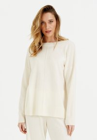 Maglione a maglia color crema con scollo rotondo e spalle scese. Presenta orlo e polsini a coste, texture liscia e cuciture minime.
