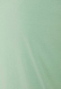 Vaalean vihreä puuvillakangas lähikuvassa, sileä rakenne, vähäinen jousto, tasainen pinta, ei havaittavissa olevia kuvioita tai malleja, pehmeä laskos.