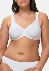 Reggiseno bianco a coste con spalline regolabili, caratterizzato da una texture liscia e una forma classica con ferretto. Abbinato a slip bianchi semplici.