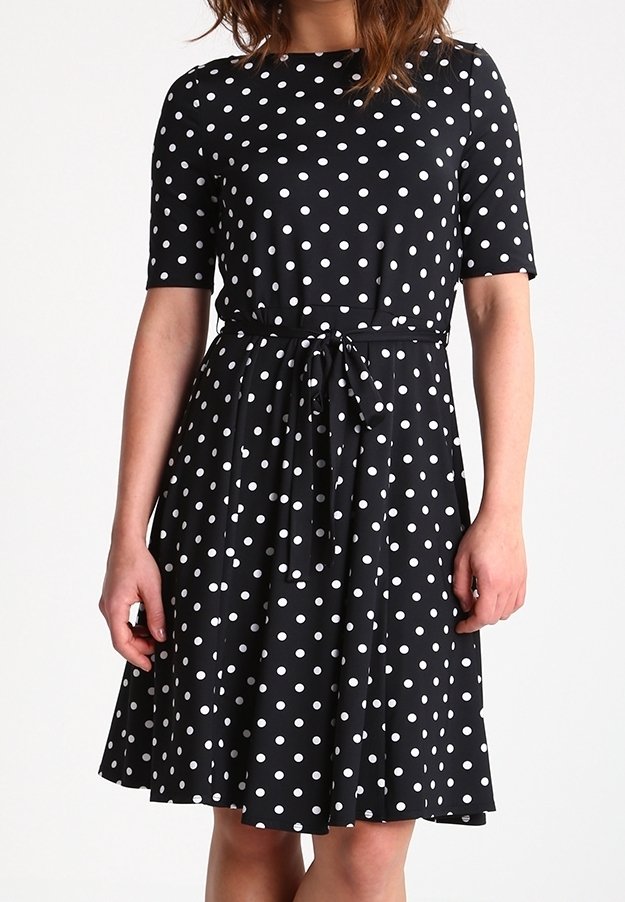 Czarna sukienka w białe kropki wykonana z miękkiego materiału, z okrągłym dekoltem, krótkimi rękawami oraz paskiem do związania w talii, rozkloszowanym dołem.