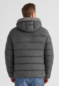 Graue Pufferjacke mit Kapuze, mit einem gesteppten Design, kontrastierenden Schulterpaneelen und strapazierfähiger Stofftextur. Rückansicht angezeigt.