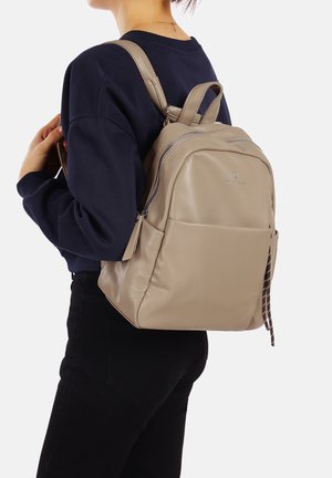 Zaino in pelle beige con una consistenza liscia e una forma arrotondata. Caratterizzato da spallacci doppi, una tasca frontale con zip e un tirazip decorativo.