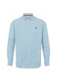 Ljusblå långärmad skjorta med knappar och knäppkrage, samt en liten broderad polo-spelare-logotyp på vänster bröst.