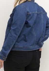 Mørkeblå denimjakke med klassisk design, der har krave, lange ærmer og diskrete syningsdetaljer. Glat, struktureret finish.