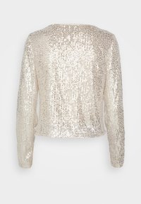 Dlouhý rukáv, třpytivý top v béžové barvě se strukturovaným, lesklým povrchem a kulatým výstřihem. Zadní strana má celoplošný design pokrytý flitry.