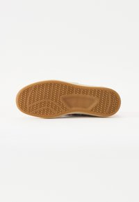 Suola in gomma con un motivo a nido d'ape, caratterizzata da una superficie texturizzata e un design flessibile, prevalentemente di colore beige.
