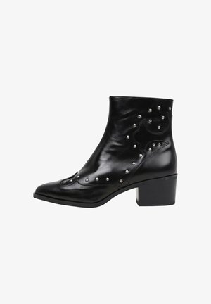 Botte de cheville en cuir noir à bout pointu, embellie de clous en métal et de découpes courbées, avec un talon bloc et une texture lisse.