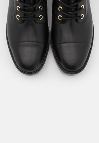 Czarne skórzane buty o gładkim wykończeniu, zaokrąglonym nosie, kontrastowym szwie i złotych oczkach na sznurówki. Klasyczny design z wypolerowanym wyglądem.