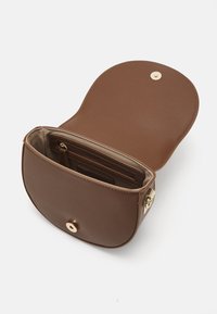 Borsa a tracolla in pelle marrone con forma arrotondata, accessori in oro e chiusura a scatto sicura. L'interno presenta scomparti per carte e una tasca con zip.