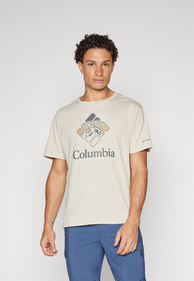 Bežs īsās piedurknes T-krekls ar grafisko dizainu, kas ietver krāsainas formas un tumši pelēku "Columbia" logo priekšpusē.