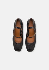 Ballerines Mary Jane tissées noires avec bout carré, bride unique, boucle dorée et semelle intérieure beige portant l’étiquette « Ángel Alarcón ».