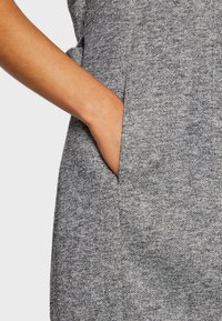 Szary materiał o fakturowanym splocie, z boczną kieszenią. Projekt obejmuje gładkie wykończenie i dopasowany krój.