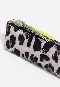 Piórnik z szarego materiału w czarny wzór lamparta, z metalowym zamkiem błyskawicznym, zielonym plecionym uchwytem i metalicznym logo.