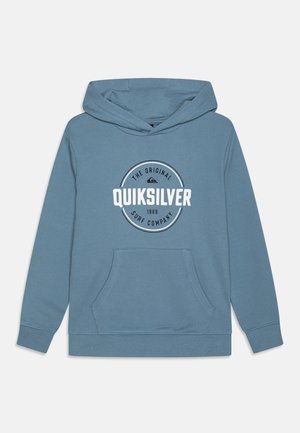 Sudadera azul con capucha, bolsillo frontal y logotipo circular blanco con texto "Quiksilver" centrado en el pecho.