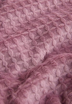 Mīksts audums maigi violetā tonī ar izceltiem dimanta raksta izcilnēm. Materiāls šķiet mīksts un pūkains ar nelielu spīdumu un dažādām dziļuma pakāpēm.