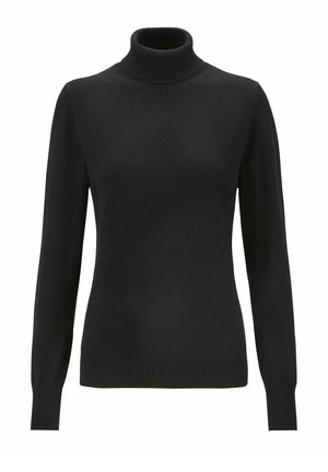 Sort turtleneck trøje med lange ærmer, parret med mørke mønstrede joggerbukser og hvide sneakers med sorte accenter.