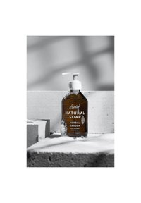 Bottiglia a pompa in vetro marrone di sapone naturale con pompa bianca e etichetta. Il testo mostra "GIARDINO ERBALE" e "FABBRICATO A ZURIGO, SVIZZERA." Bolle visibili.
