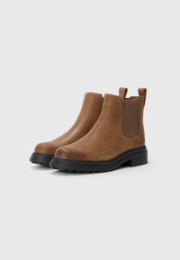 Braune Leder-Stiefel bis Knöchelhöhe mit elastischen Seiteneinsätzen, runder Spitze und dicker schwarzer Gummisohle. Minimalistisches Design mit Zuglaschen für einfaches Anziehen.