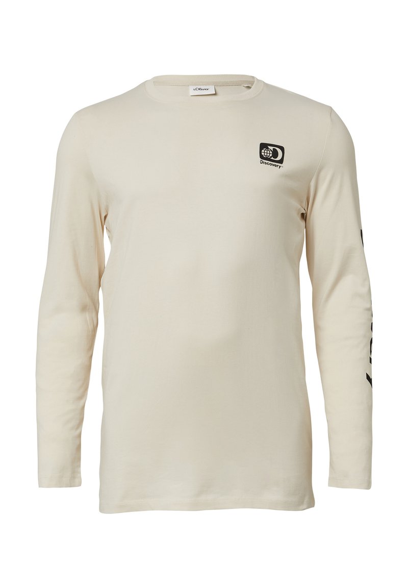 Beige blouse met lange mouwen en een klein zwart Discovery-logo op de borst, en een zwart tekstontwerp dat langs de linker mouw loopt.