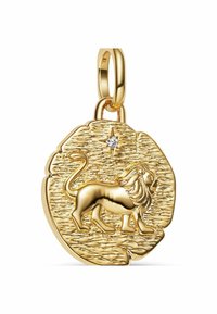 Zlatni amulet z obsežnim graviranim levom in majhno gemasto obliko, ki je nameščena nad njim, pritrjena na poliran zlat obroč.