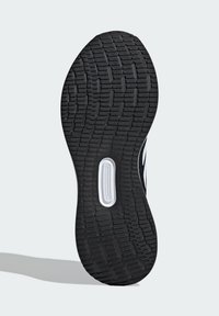 Black rubber shoe sole with textured tread patterns and a white accent along the side, featuring a recessed logo area.