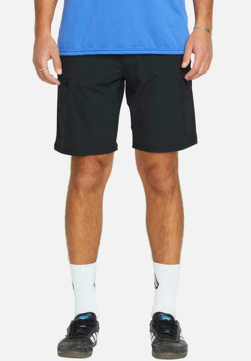 Shorts de carga negros de tela, con dos bolsillos laterales y un corte relajado, combinados con una camiseta azul y zapatillas negras.