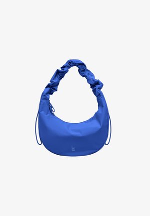 Niebieska torebka w kształcie półksiężyca z marszczonym paskiem na ramię i zamkiem błyskawicznym, małe logo "GOT BAG" blisko dolnego środka.