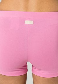 Różowe bawełniane szorty o miękkiej, gładkiej fakturze. Charakteryzują się prostym wzornictwem i małą metką z tyłu. Dopasowany krój.