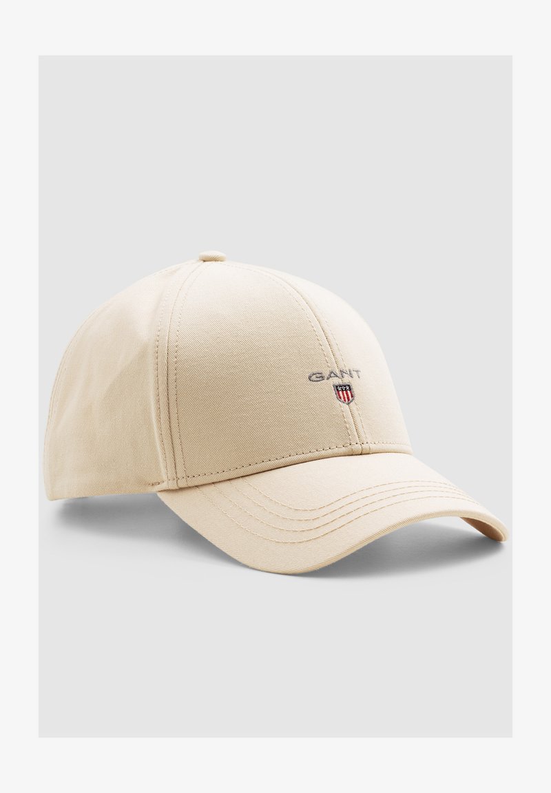 Beige bomuldsbaseballcap med buet skygge, syede paneler og et lille GANT-logo med skjoldsymbol på forsiden.