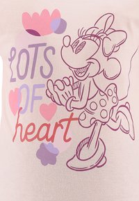 Light pink t-shirt featuring a graphic of a cartoon character with black outlines, wearing a polka dot dress, and the text "LOTS OF heart" in colorful font.