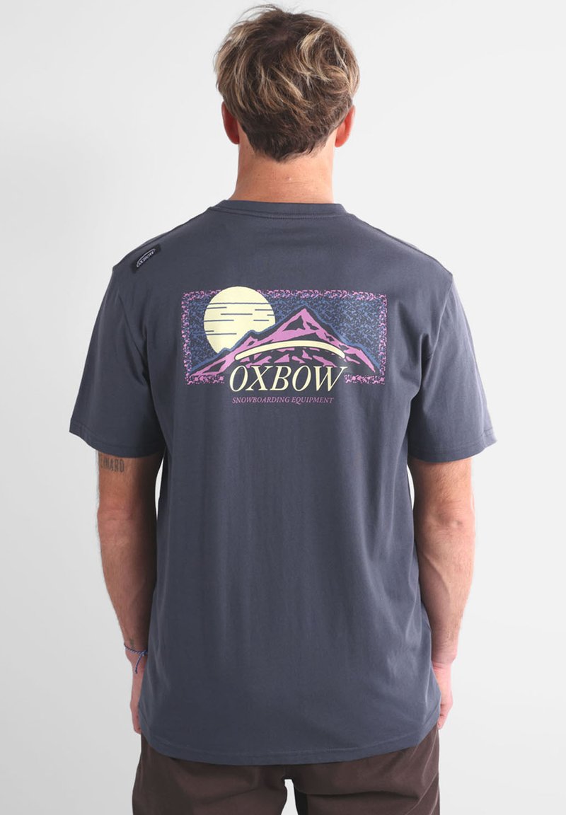 T-shirt gris à manches courtes avec un design graphique de montagnes et d'une lune, accompagné du texte "OXBOW". Tissu doux et coupe décontractée.