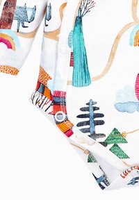 Hvid onesie med farverige illustrationer af træer, dyr og skyer. Den har korte ærmer og trykknapper i bunden.