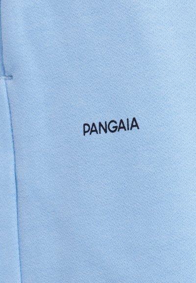 Hele sinine kangas, millel on väiksed mustad "PANGAIA" kirjaga tikandid õmbluse lähedal.