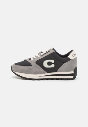 Grijze en zwarte sneaker met witte veters, een groot "C"-logo aan de zijkant en een zwart rubberen zool met patroon.