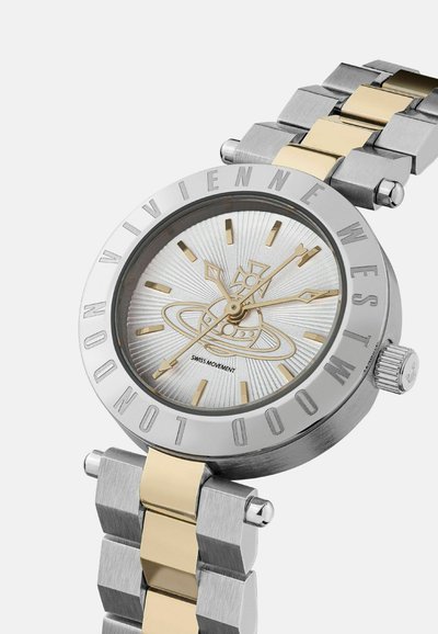 Zilveren en goudkleurige horloge met een ronde kast, een gestructureerde zilveren wijzerplaat, bold uurmarkeringen en een metalen schakelband met afwisselende afwerkingen.