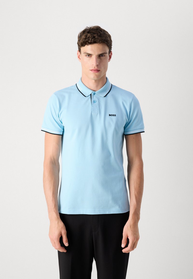 Polo en coton de couleur bleu clair avec un col à bord noir et blanc, deux boutons et un petit logo noir sur la poitrine.