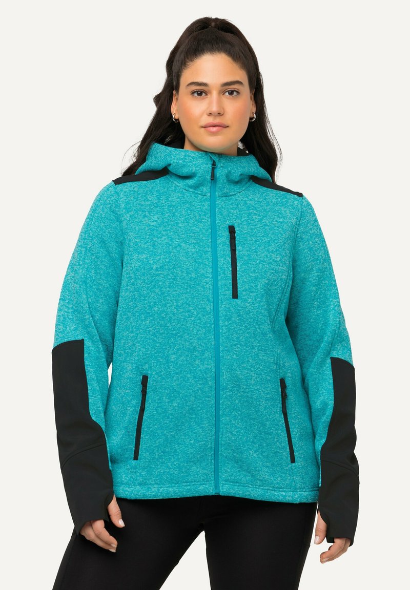 Giacca teal con zip, realizzata in tessuto testurizzato, con accenti neri sulle spalle e sui polsini, dotata di tasche con zip sui lati e sul petto.