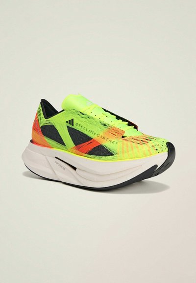 Chaussure de sport néon verte et noire avec une tige texturée, de vives accents orange et une semelle intermédiaire épaisse blanche avec une semelle extérieure noire.