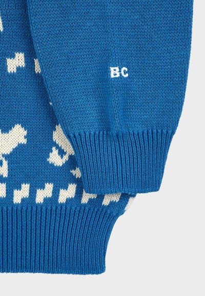 Modrá pletená svetrová s textúrovaným vzorom, so bielymi zvieracími motívmi a rebrovanými manžetami. Malé biele logo "BC" na rukáve.