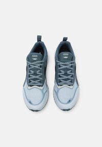 Chaussures de sport bleu clair avec un design en mesh, accentuées par des éléments bleu foncé et gris. Elles comportent des lacets plats et une languette au talon.