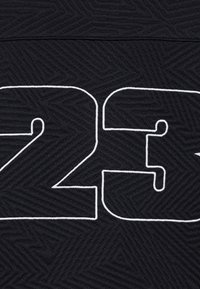 Fekete textil, amelyen szerkezeti halszálka minta látható, és a középen nagy fehér "23" számok találhatóak.