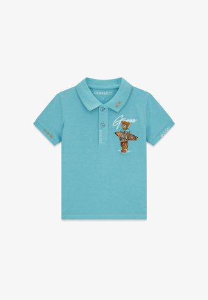 Polo azzurro chiaro a maniche corte con bottoni, orsetto ricamato che tiene un cartello con la scritta "GUESS" e cuciture decorative sulle maniche e sul colletto.