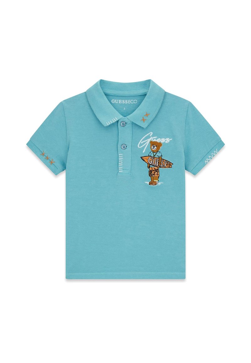 Polo azzurro chiaro a maniche corte con bottoni, orsetto ricamato che tiene un cartello con la scritta "GUESS" e cuciture decorative sulle maniche e sul colletto.