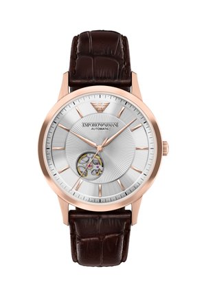 Rundes silbernes Zifferblatt mit roségoldfarbenen Markierungen und Zeigern, braunem Lederarmband und sichtbarem automatischem Uhrwerk nahe 8 Uhr.