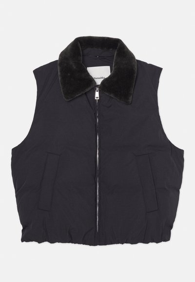 Črna brezrokavnica z mehkim umetnim krznom okoli ovratnika, zadrgo in dvema sprednjima žepoma; gladka tekstura z rahlo napihnjeno silhueto.