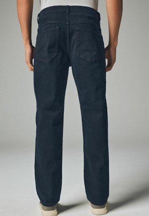 Ciemnoniebieskie spodnie dżinsowe o prostej nogawce, z dwoma tylnymi kieszeniami i subtelnymi detalami szwów. Materiał z mieszanki bawełny.