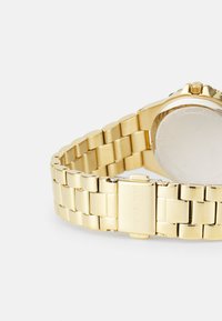 Reloj de metal dorado con un diseño de pulsera eslabonada y un acabado pulido, y una caja redonda. Incluye un cierre con detalle de la marca.