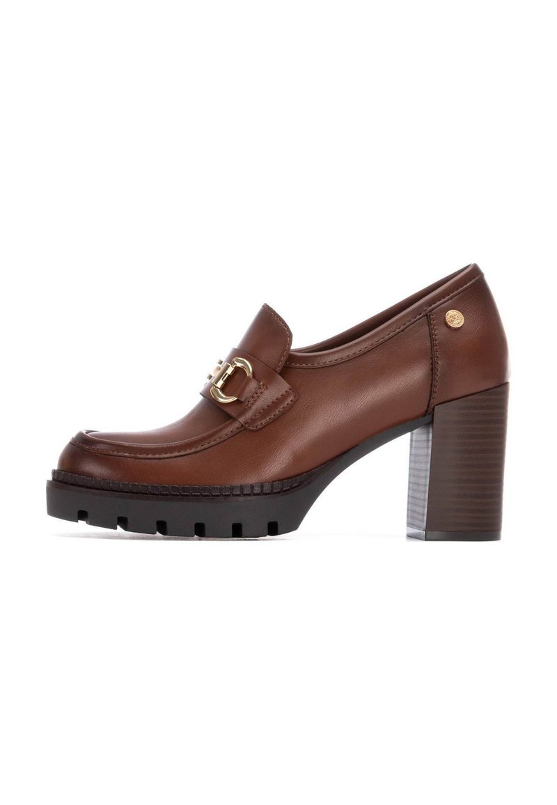 Moc shoes de cuero marrón con tacón, punta redondeada, hebilla decorativa, plataforma negra texturizada y tacón estriado. Acabado pulido.