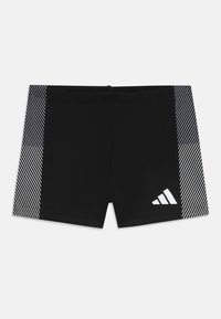 Shorts de bain noirs avec des accents rayés diagonaux blancs sur les côtés. Fabriqués à partir d'un matériau lisse et extensible. Logo Adidas affiché.