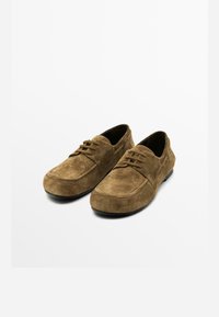Bruine suède schoenen met ronde neuzen, minimale veters, gestructureerd oppervlak en rubberen zolen. Functioneel ontwerp met een casual uitstraling.